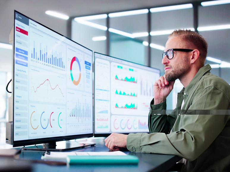 Professional analyzing performance charts and AI reporting dashboards on multiple monitors