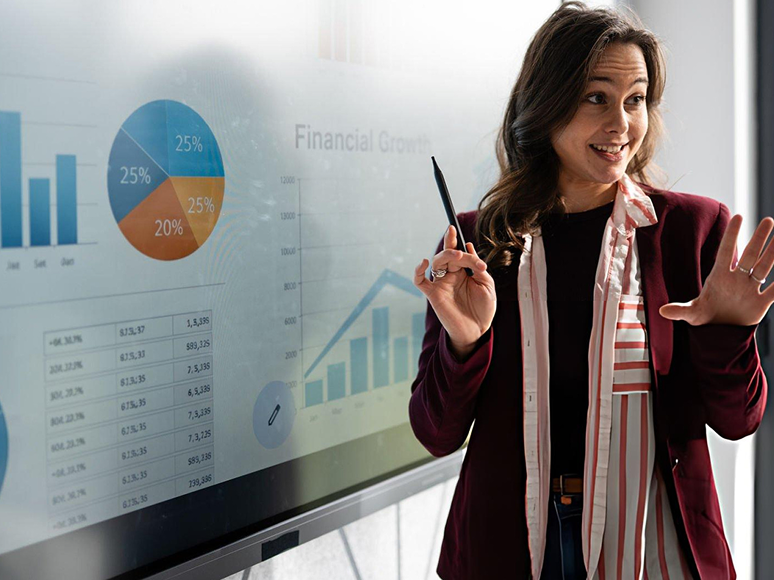 Female presenter demonstrating financial growth charts and sales enablement strategies on an interactive screen