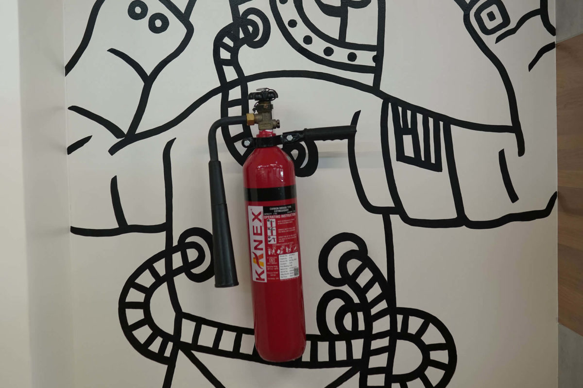 Painted Fire Extinguisher with Graffiti on Wall